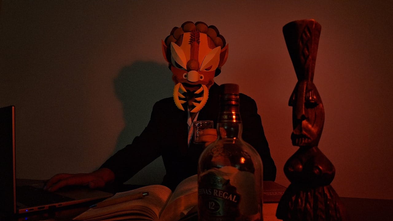 person with a mask like a bug face with a laptop and a glass